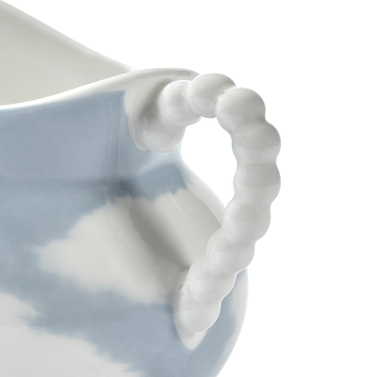 Close-up of a porcelain pitcher with a light blue and white marbled pattern, featuring a distinctive twisted ribbed handle on a white background.