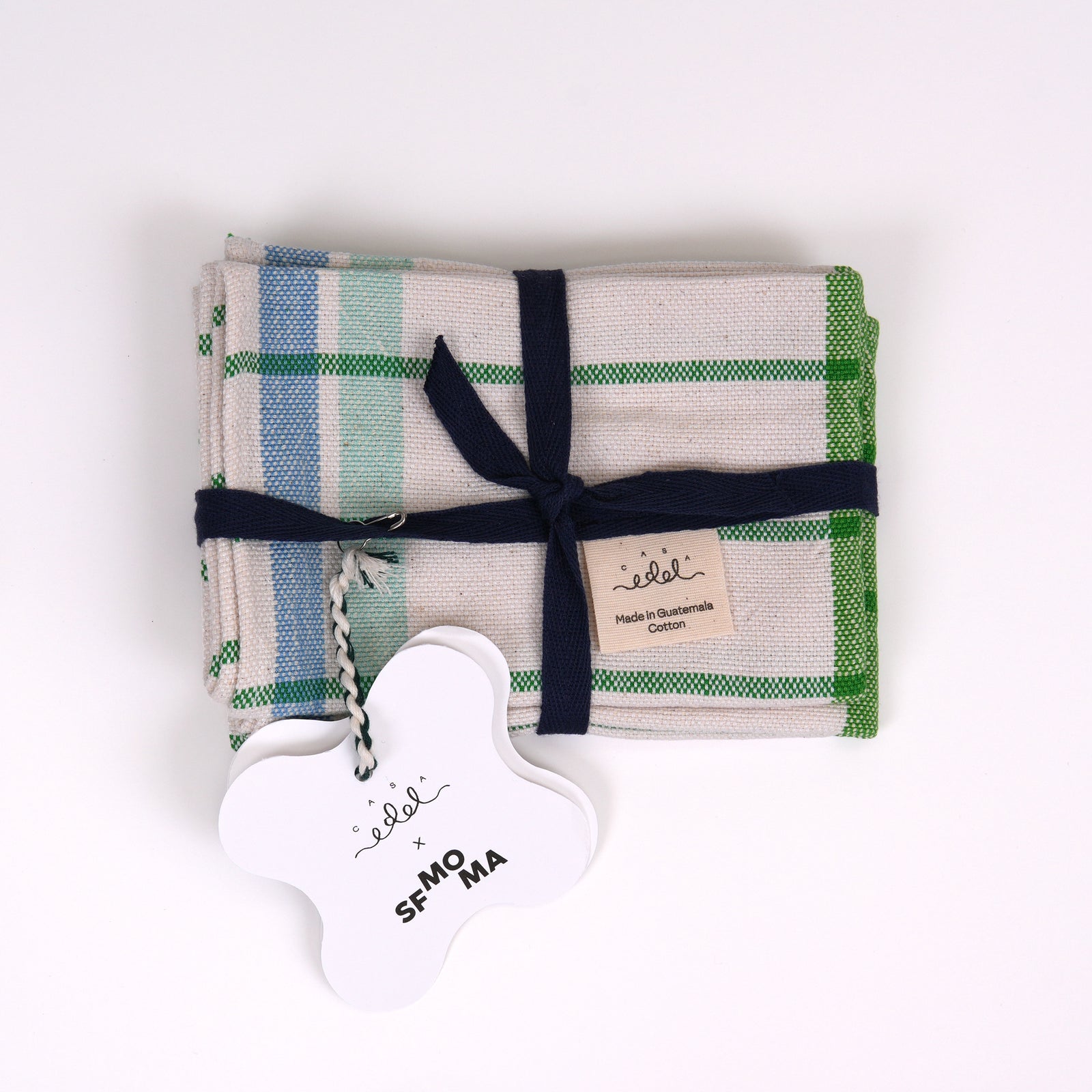 Two placemats with a white base, featuring a green vertical stripe, green horizontal stripes, and blue vertical stripes on a plain white background.