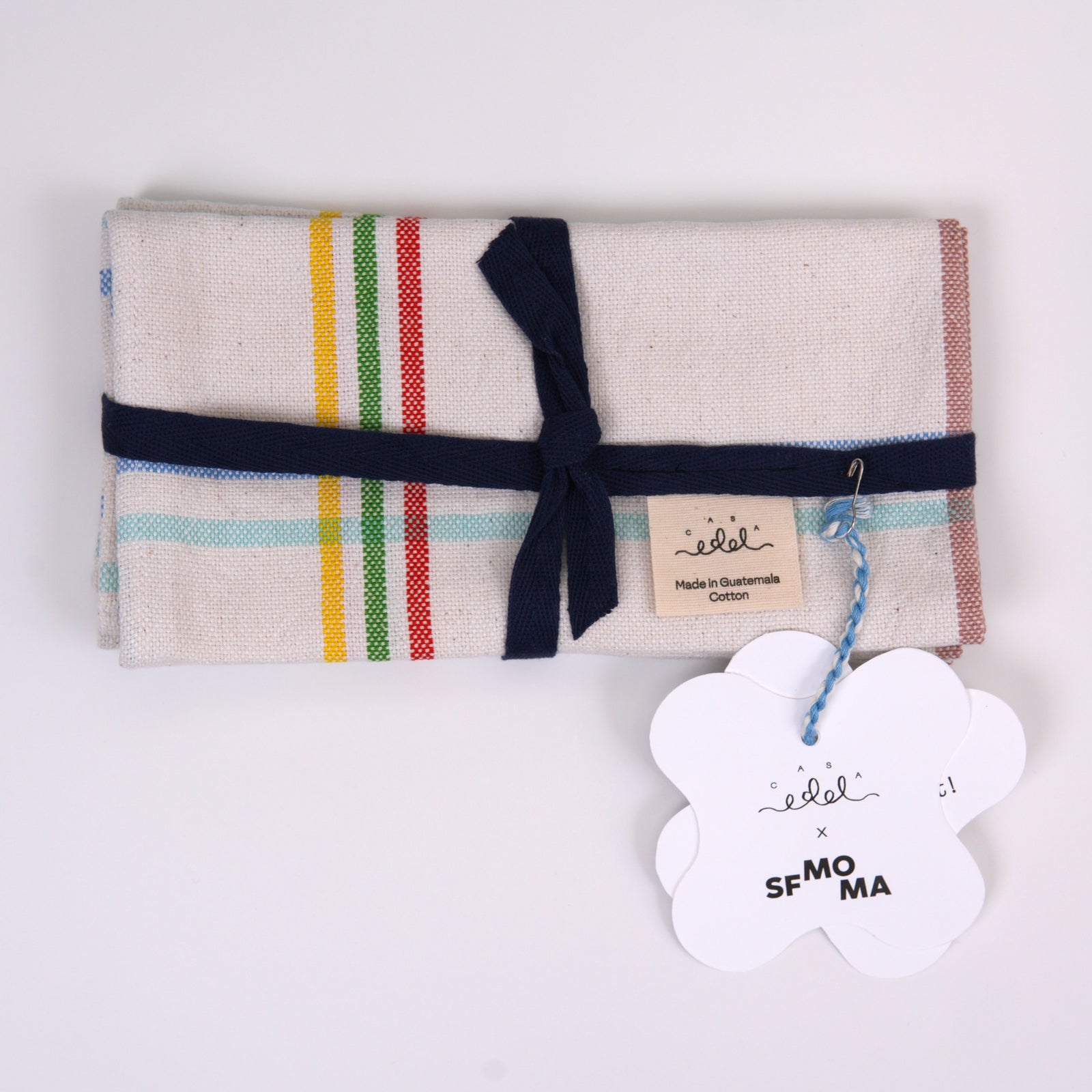 Two rectangular napkins with a white base and a multicolor plaid pattern of blue, green, red, yellow, and brown stripes, displayed side-by-side on a white background.