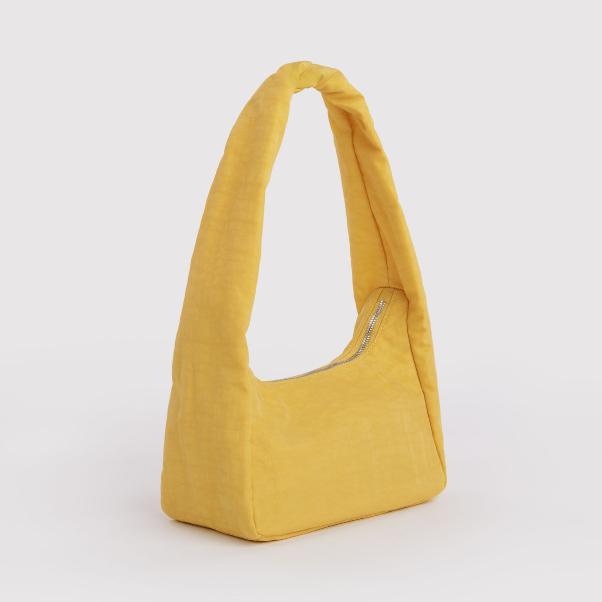 A mustard yellow fabric shoulder bag with a single integrated strap and a silver zipper, shown on a light gray background.