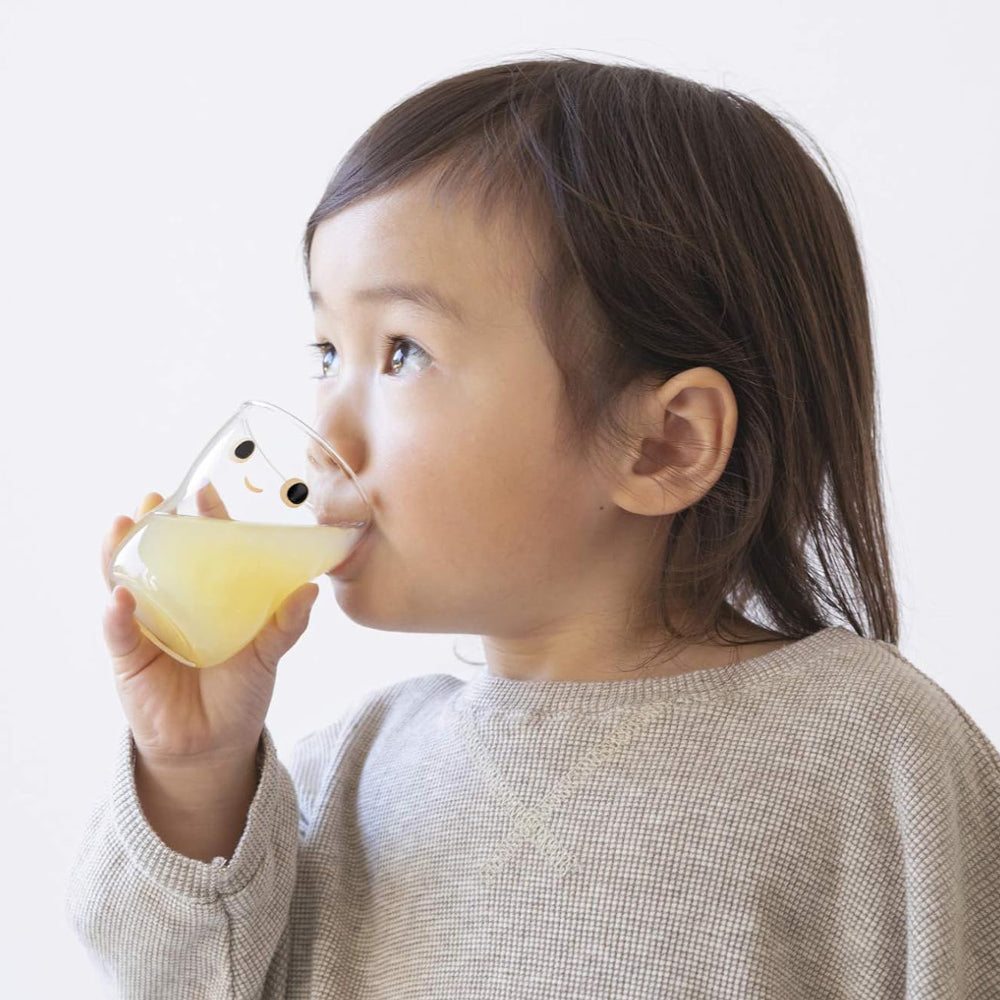 Toddler drinking a glass of juice.