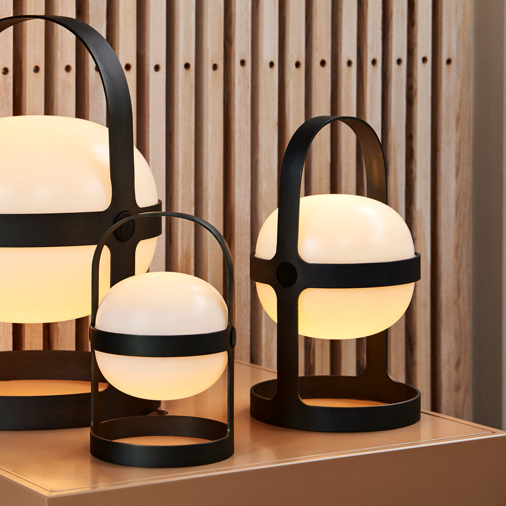 Modern table lamps with black metal frames and white glass shades on a wooden surface.