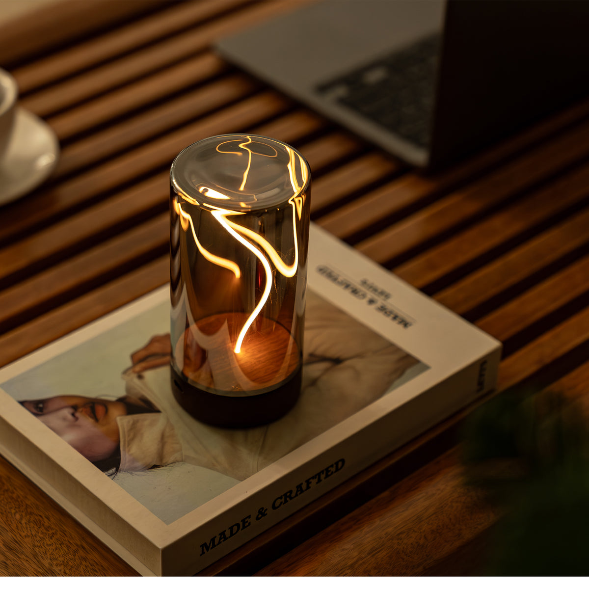 Small lit lamp on a book with a blurred laptop in the background