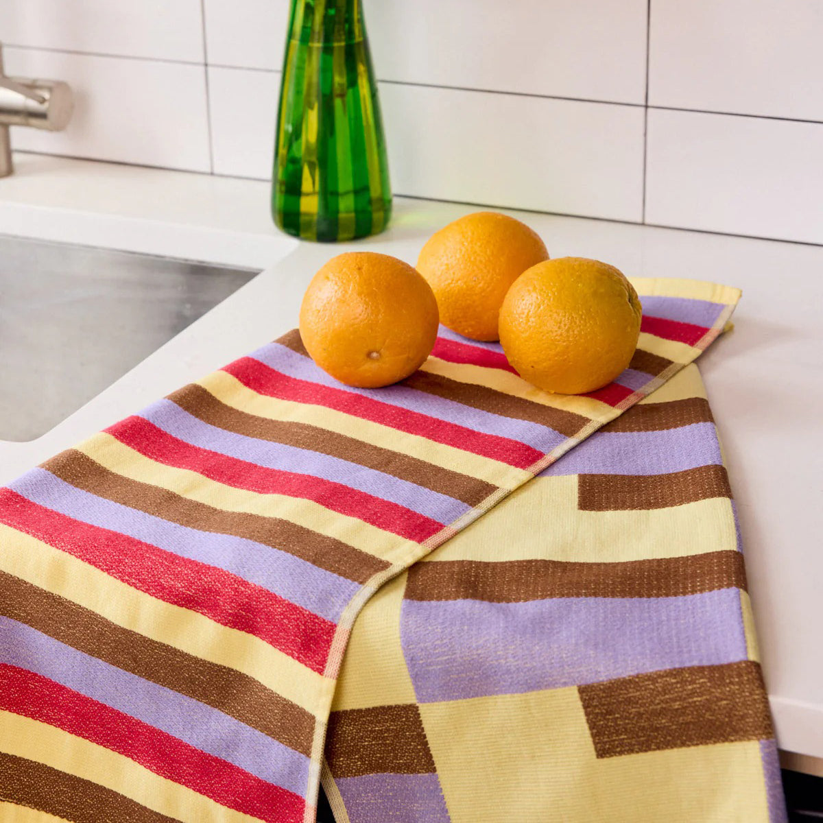 Two striped towels, one with red, purple, and brown stripes and the other with a checkered pattern, on a white background.