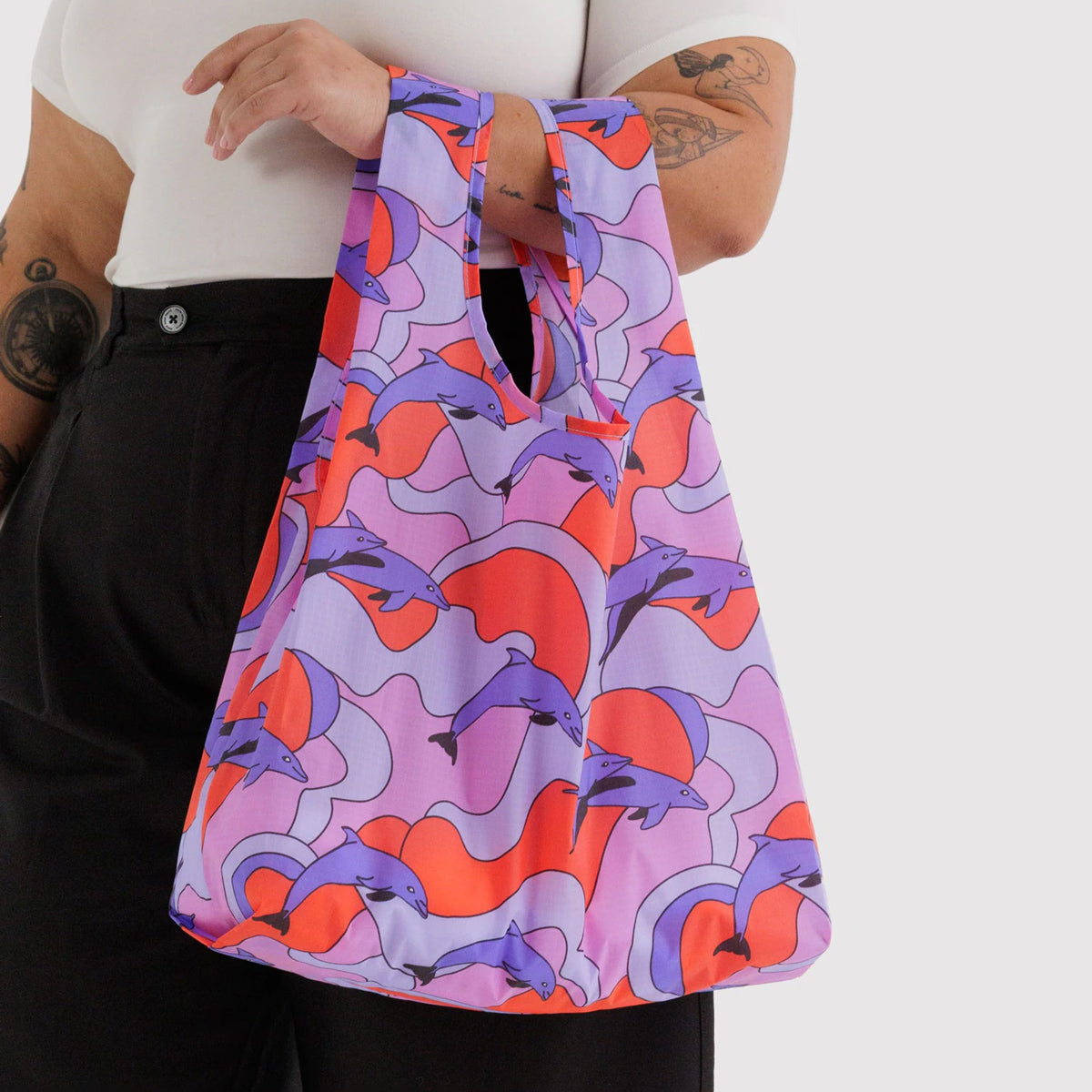 Person holding a colorful bag with abstract dolphin design on a white background