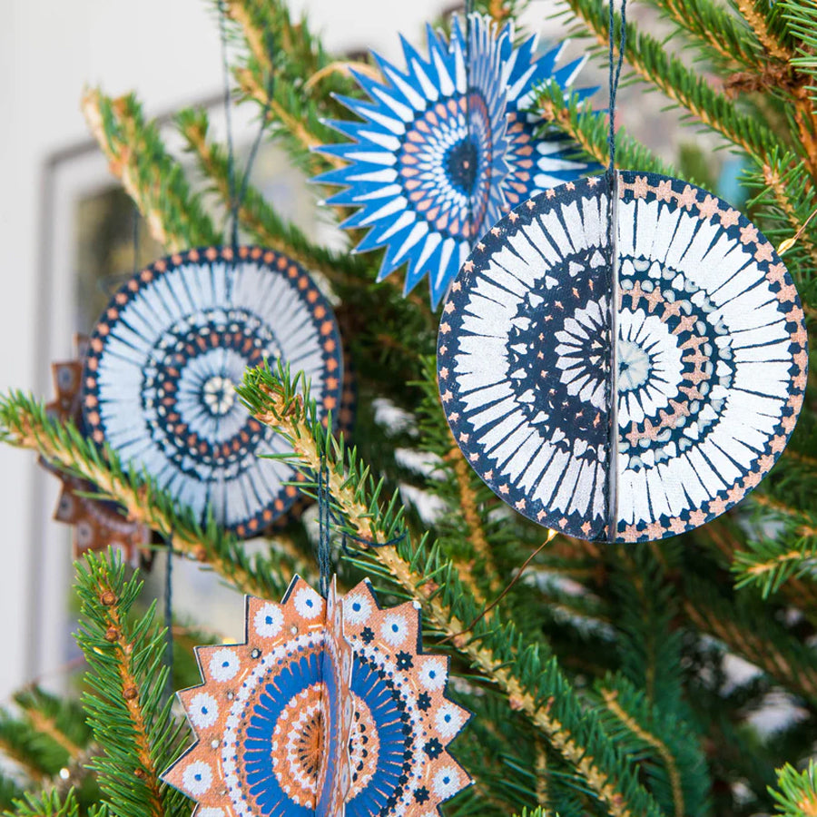 Decorative circular ornaments with spiral patterns hanging on a Christmas tree.