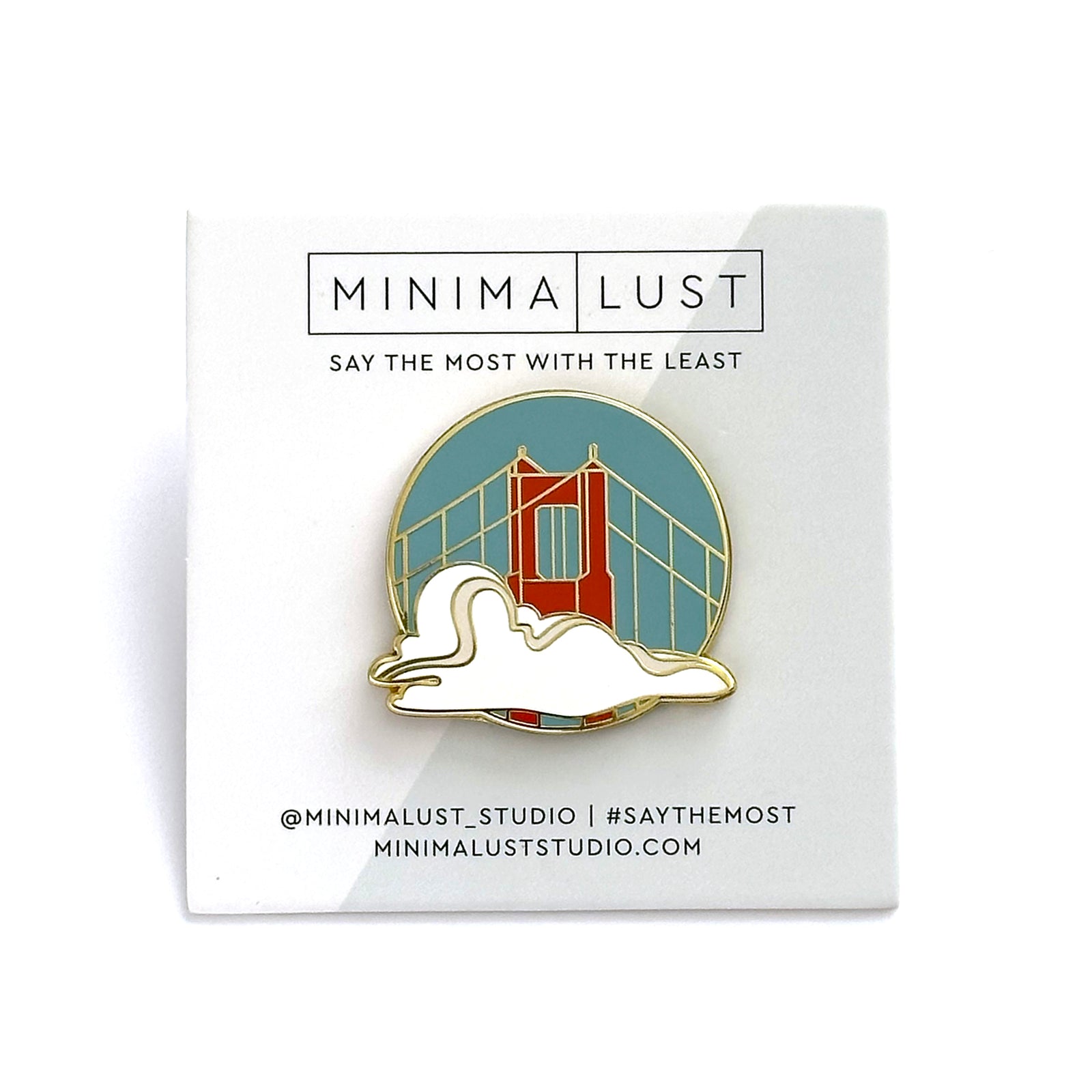 Pin with a design of a fog and bridge, branded as Minima Lust on a white card.