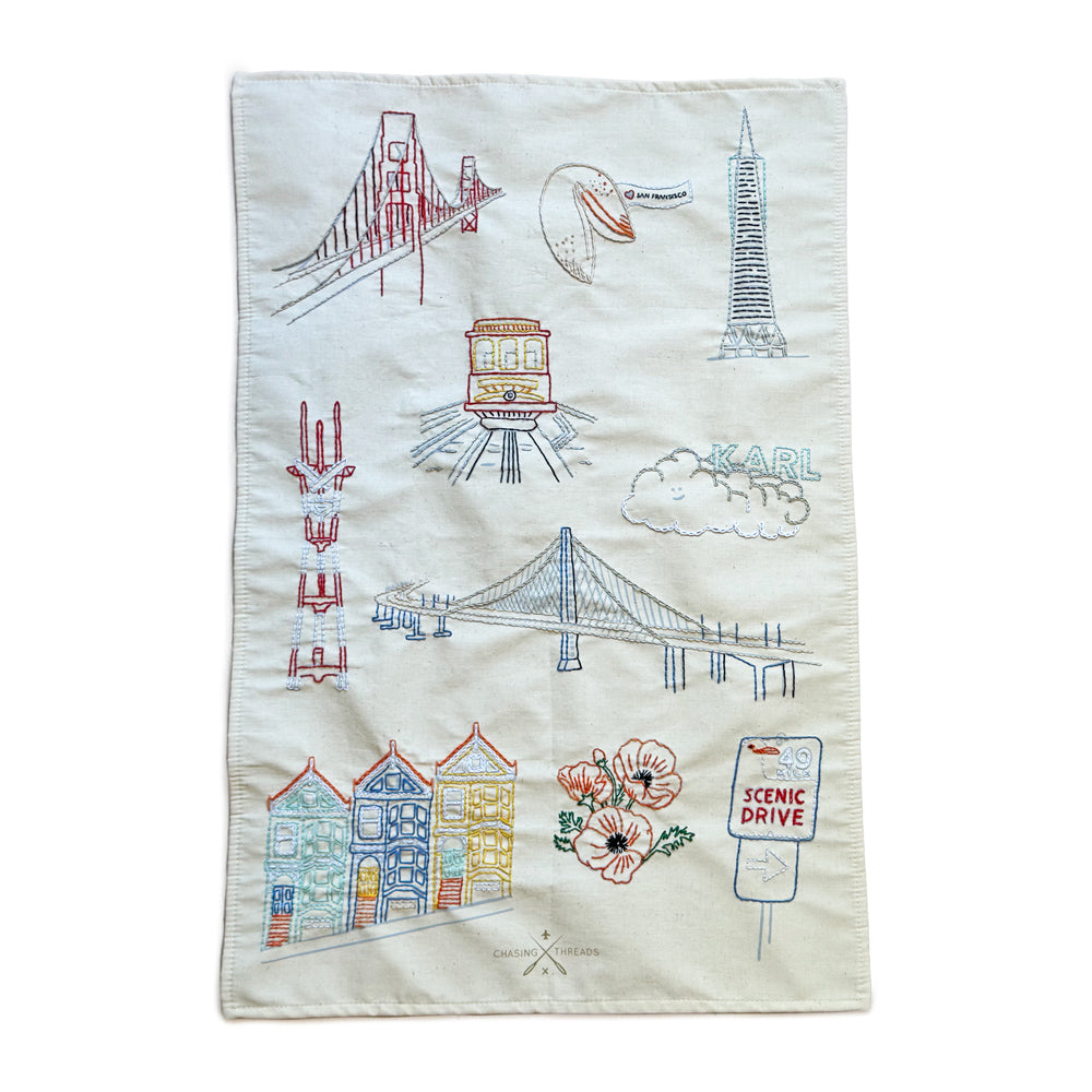 Embroidered tea towel with San Francisco-themed designs on a white background