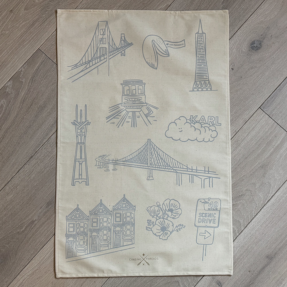 Embroidered tea towel with San Francisco-themed designs on a white background