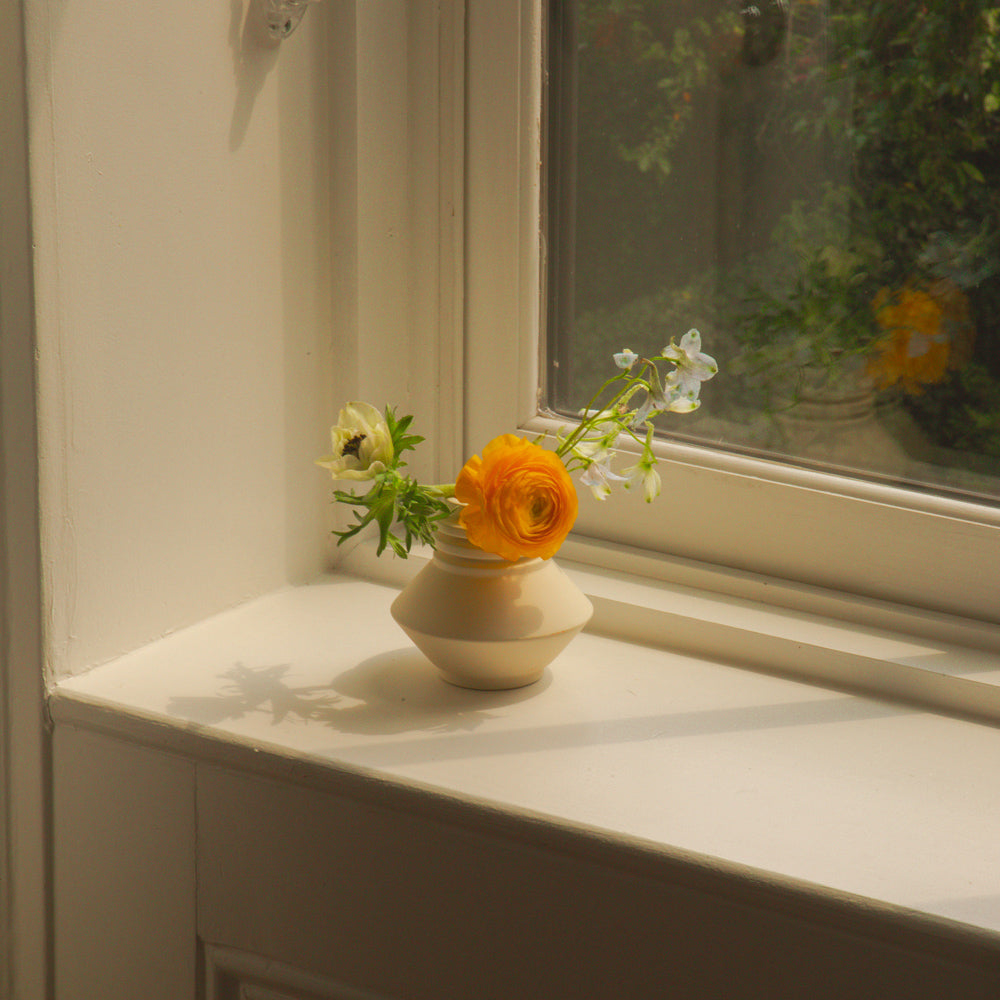 Vase on window sill with flowers.