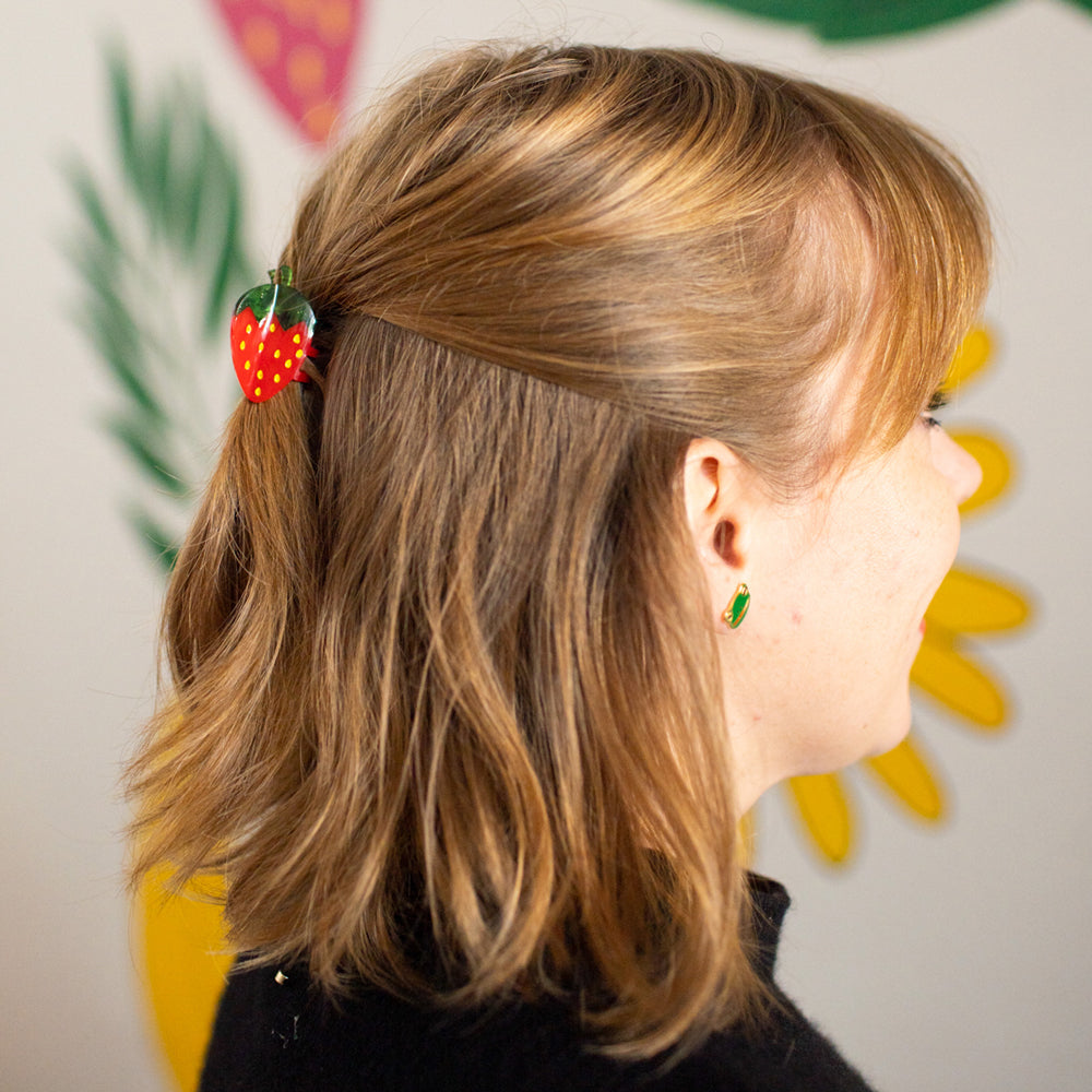 Person with a strawberry hair clip in their hair, with a colorful background
