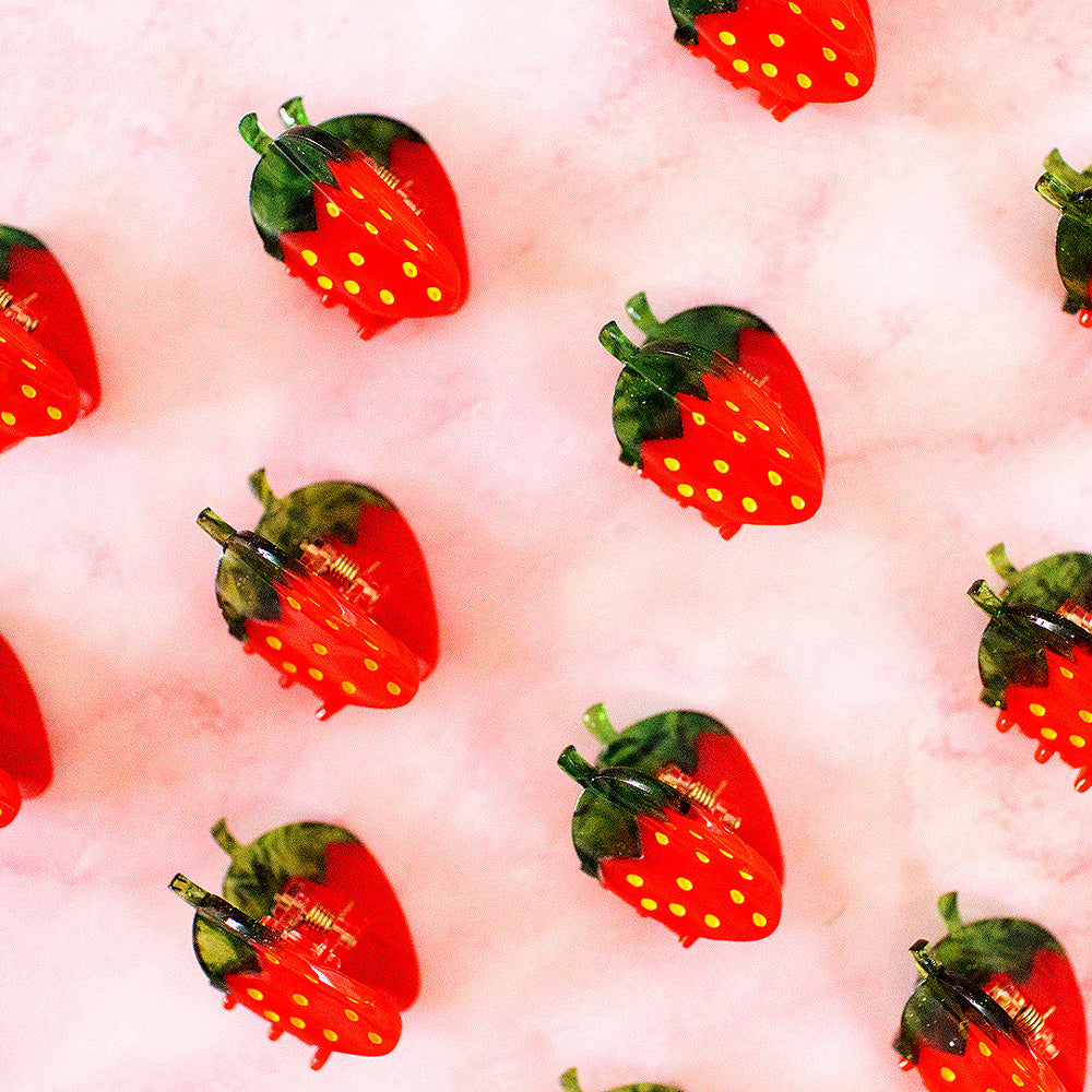 Pattern of red strawberries with green leaves on a pink background
