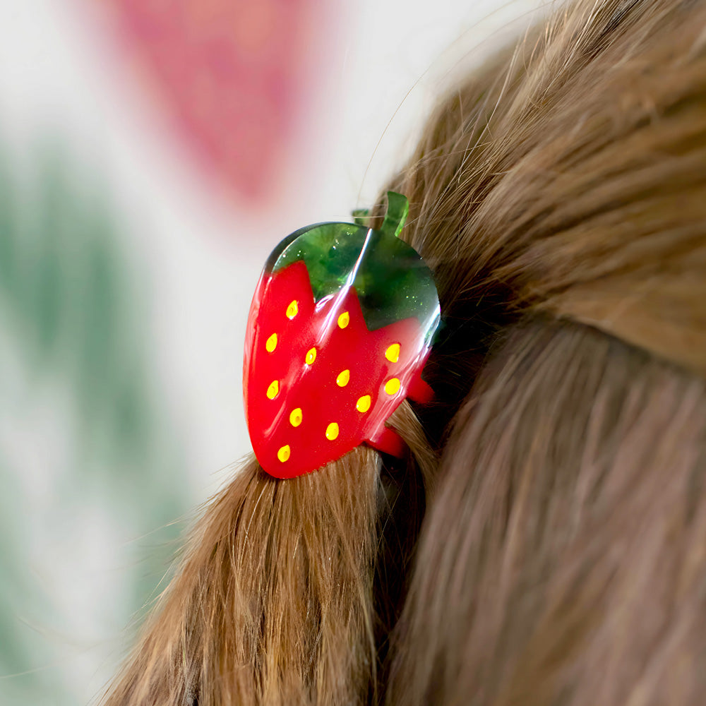 Strawberry-shaped hair clip on a person's hair with a blurred background