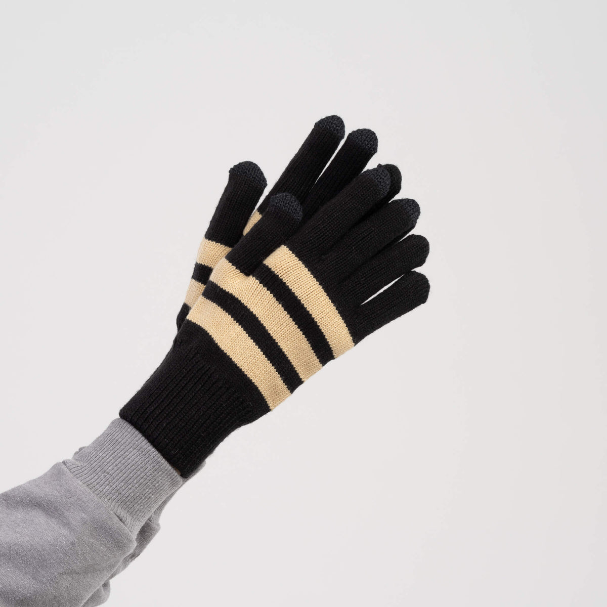 A pair of black knit gloves with two horizontal beige stripes on the back of the hands, displayed against a light gray background.