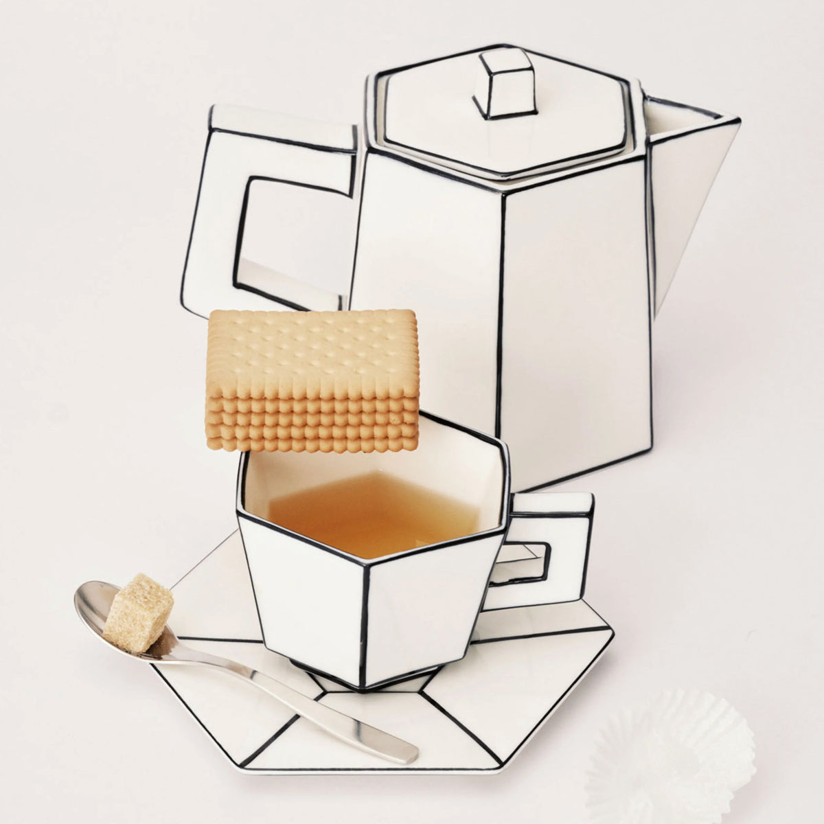 Geometric tea pot with a cup and cookies on a white background