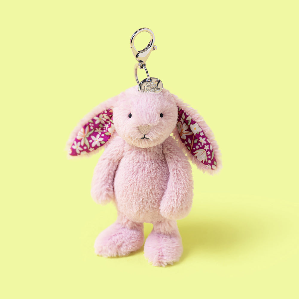 Pastel purple plush bunny keychain with floral wings on a yellow background