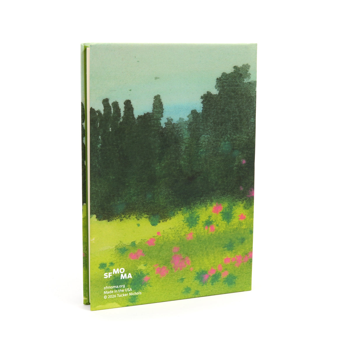 A front cover notebook featuring a landscape painting of a green field with pink flowers and a dark tree line under a pale sky, shown on a white background.