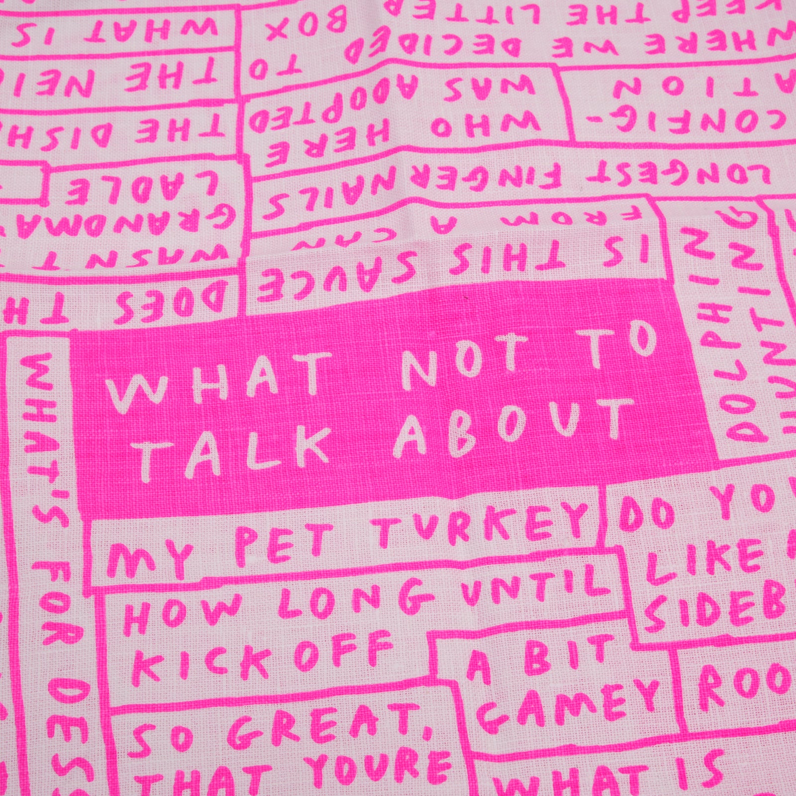 A stack of square whitenapkinswith red borders and pink printed text and illustrations, including a central pink box reading 'WHAT NOT TO TALK ABOUT'.