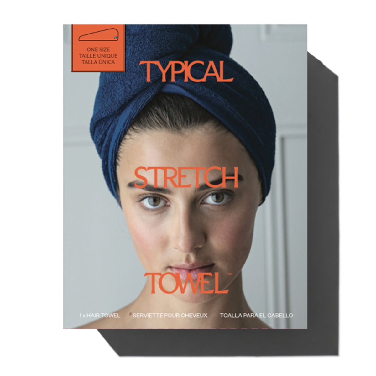 A hair towel packaging box featuring a close-up photo of a woman with a dark blue towel wrapped around her hair. The box has a light gray background with orange text reading 'TYPICAL STRETCH TOWEL' and a small orange label in the top left corner.