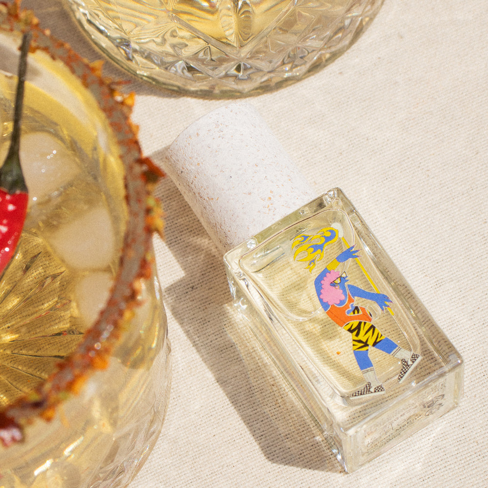 Maison Matine Parfum 15ml bottle in a clear glass container with a colorful abstract illustration, presented in a brown kraft paper sleeve on a white background.