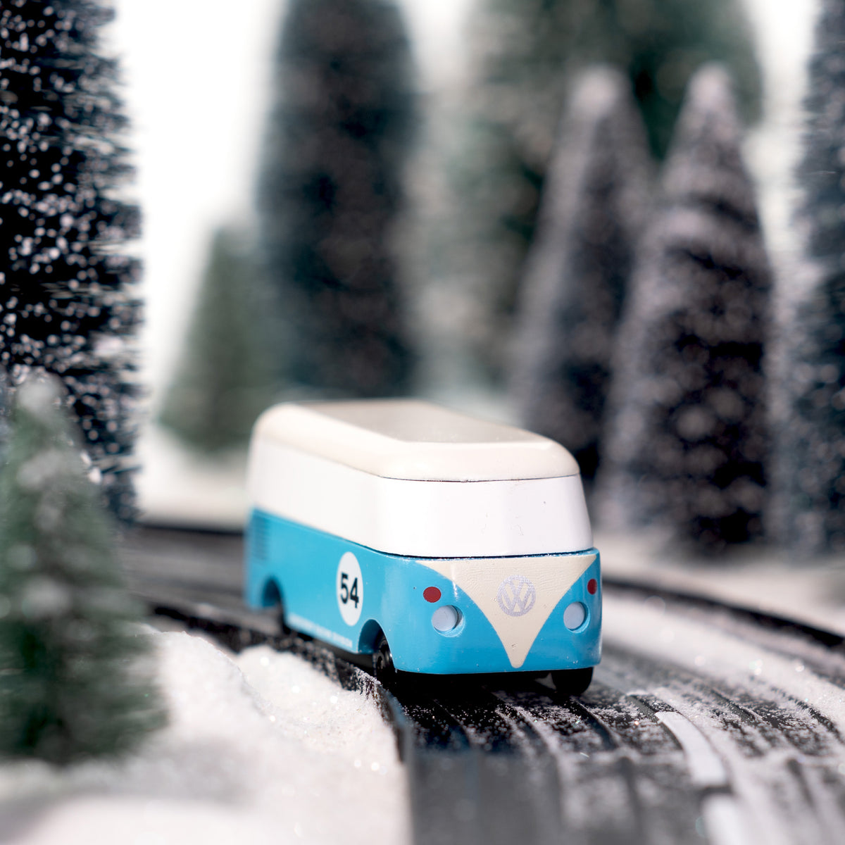 Toy bus on a snowy road with blurred trees in the background