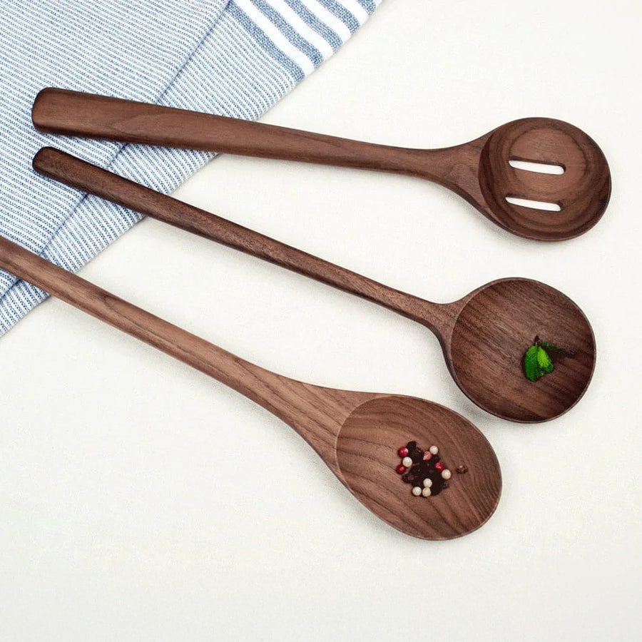 Set of three wooden spoons with decorative elements on a white surface.