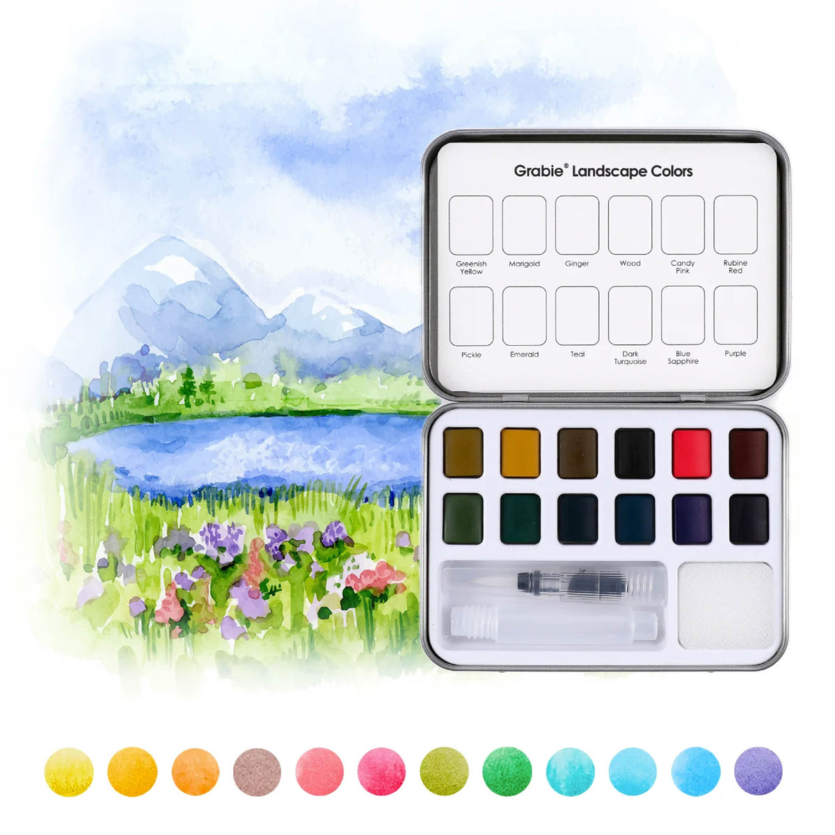 A metal watercolor painting set shown open, with labeled color wells and a small brush, placed over a painted landscape scene of mountains, lake, and flowers. A row of circular color swatches appears along the bottom.