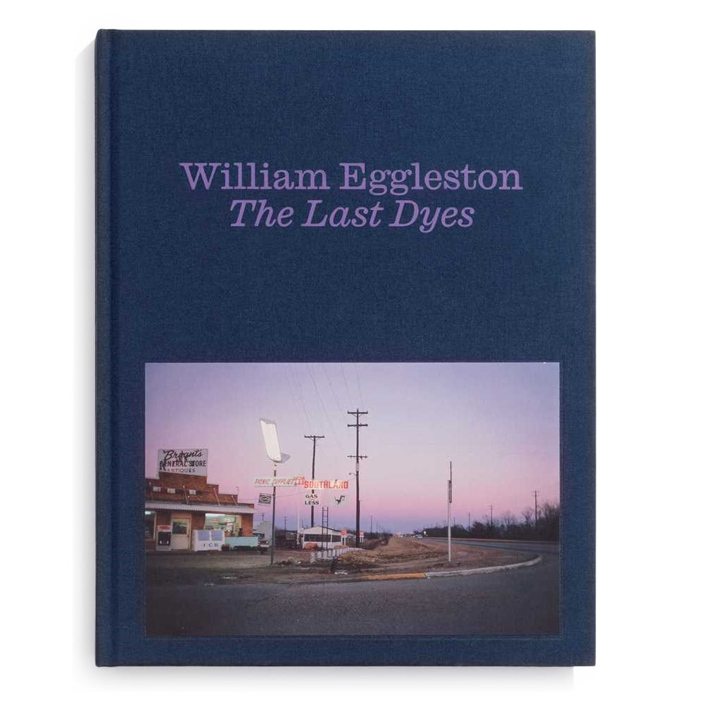 Book cover of 'The Last Dyes' by William Eggleston with a photograph of a small town scene on a white background.