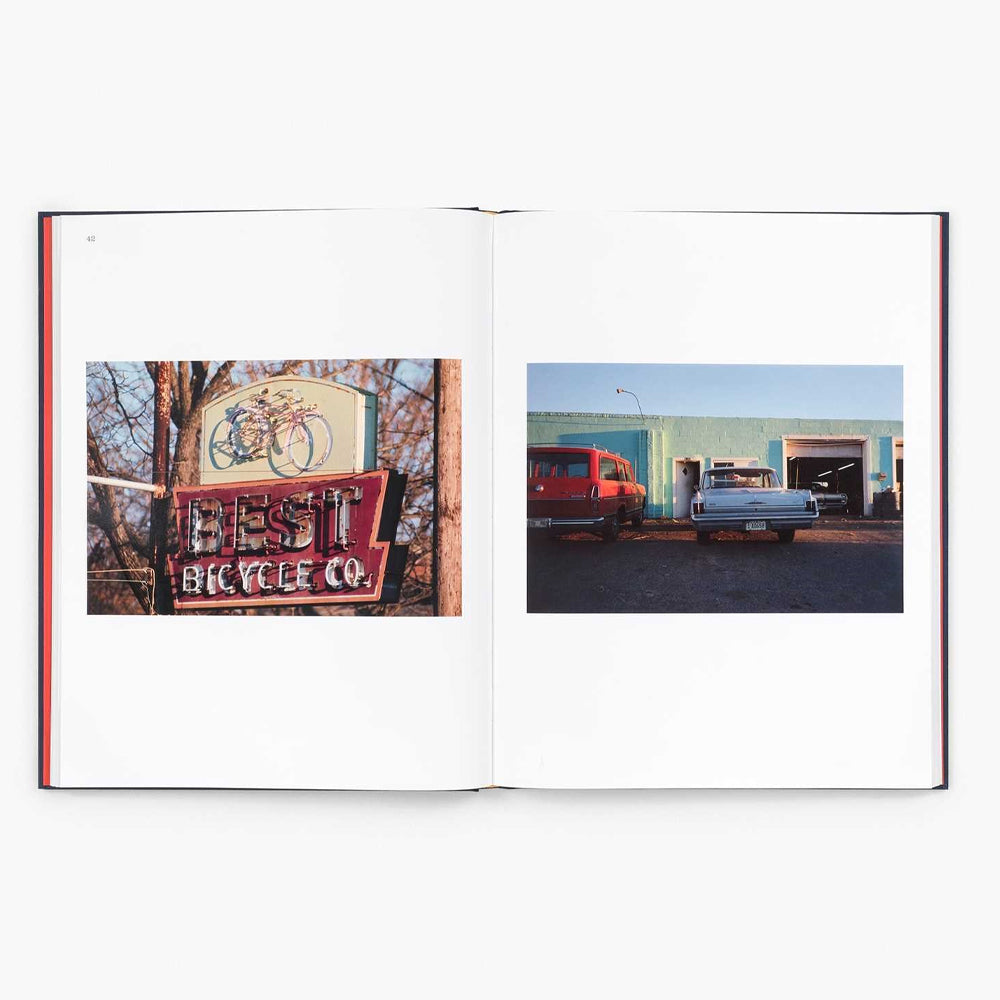 Open book showing two photographs: one of a sign for 'Best Bicycle Co.' and another of a red truck and white car in front of a building.