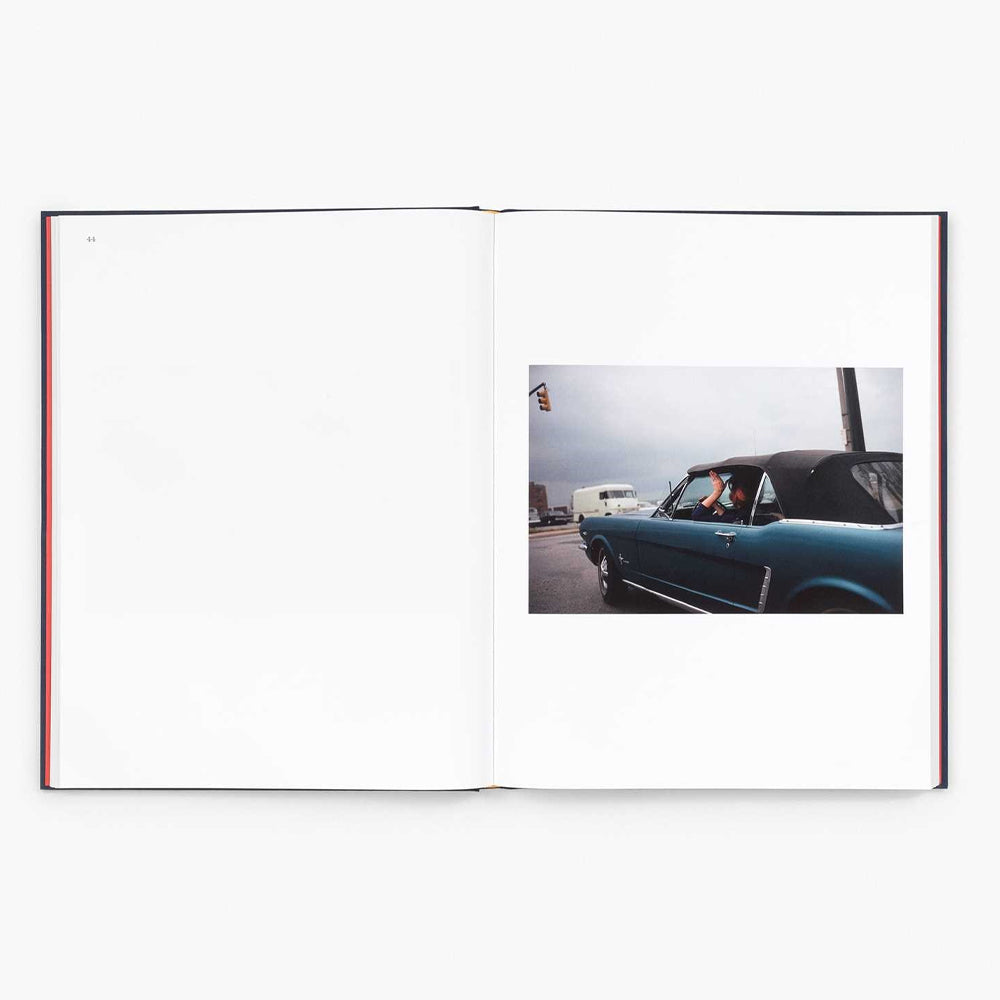 Open book showing a photograph of a vintage car on a road with a white background