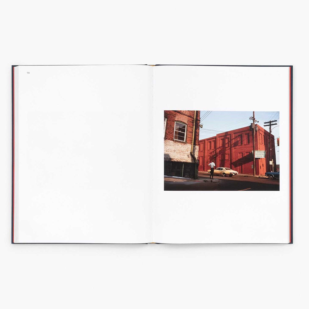 Open book showing a photograph of a street scene with a red building and a person.