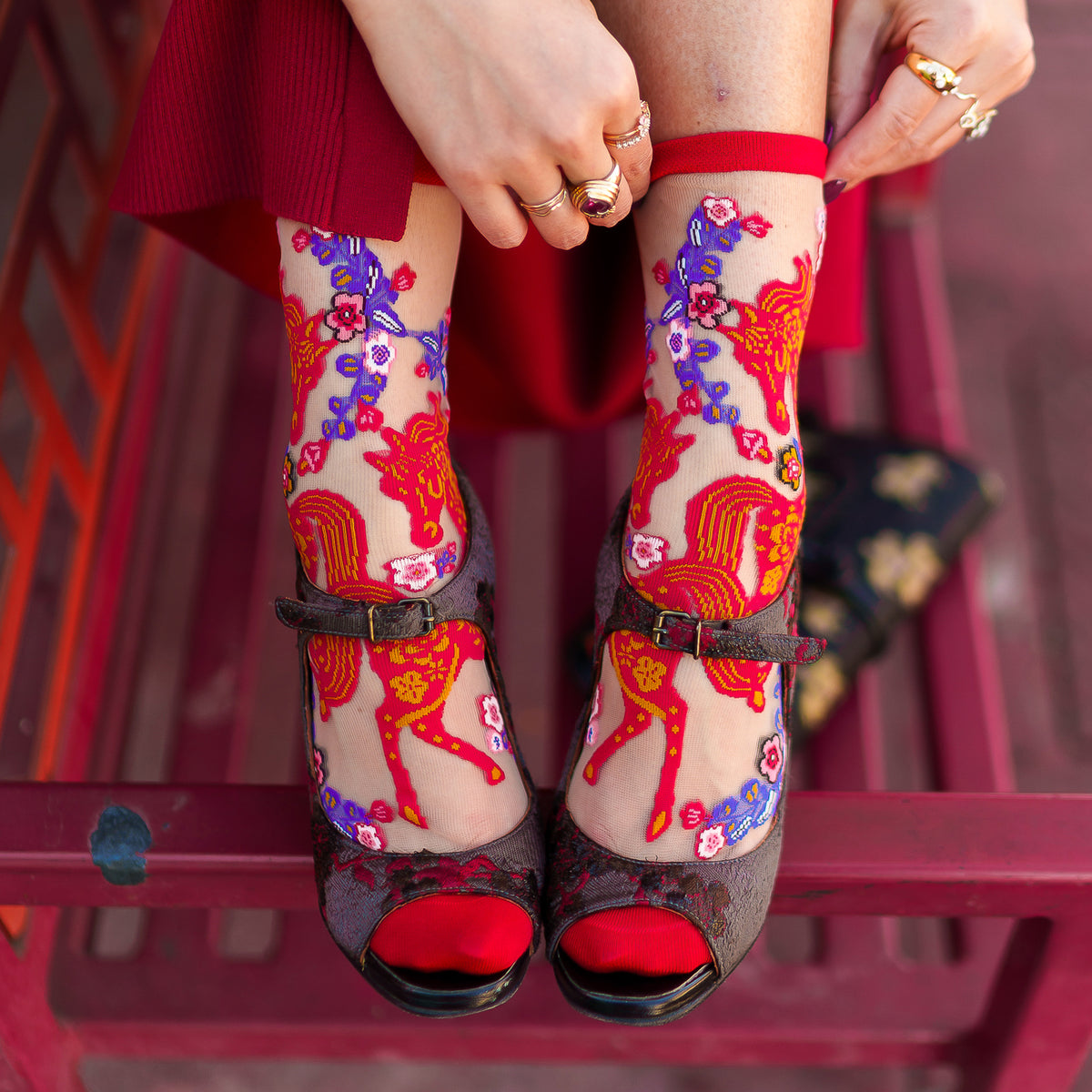Colorful horse and floral-patterned socks with black shoes on a red background