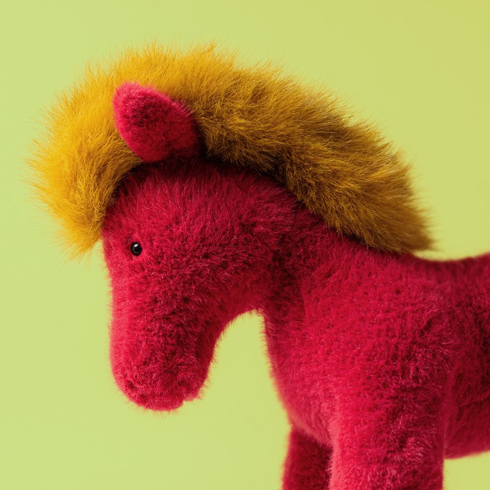 Red plush horse with yellow mane on a green background