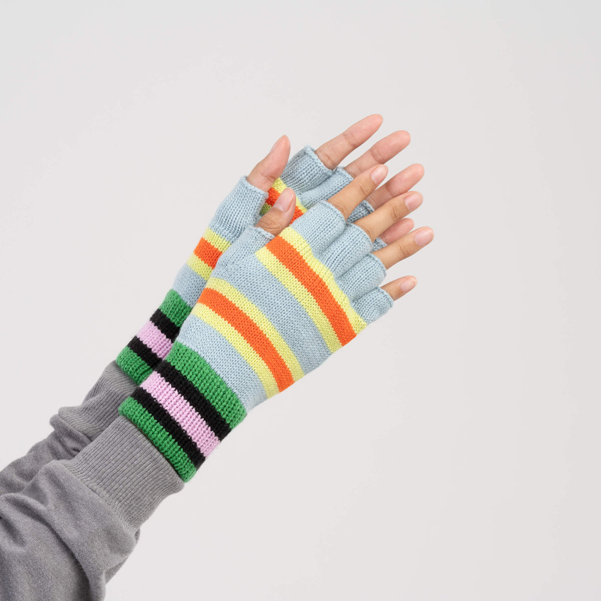 A pair of fingerless knit gloves with horizontal stripes in light blue, green, yellow, orange, pink, and black, displayed on a clean white background.