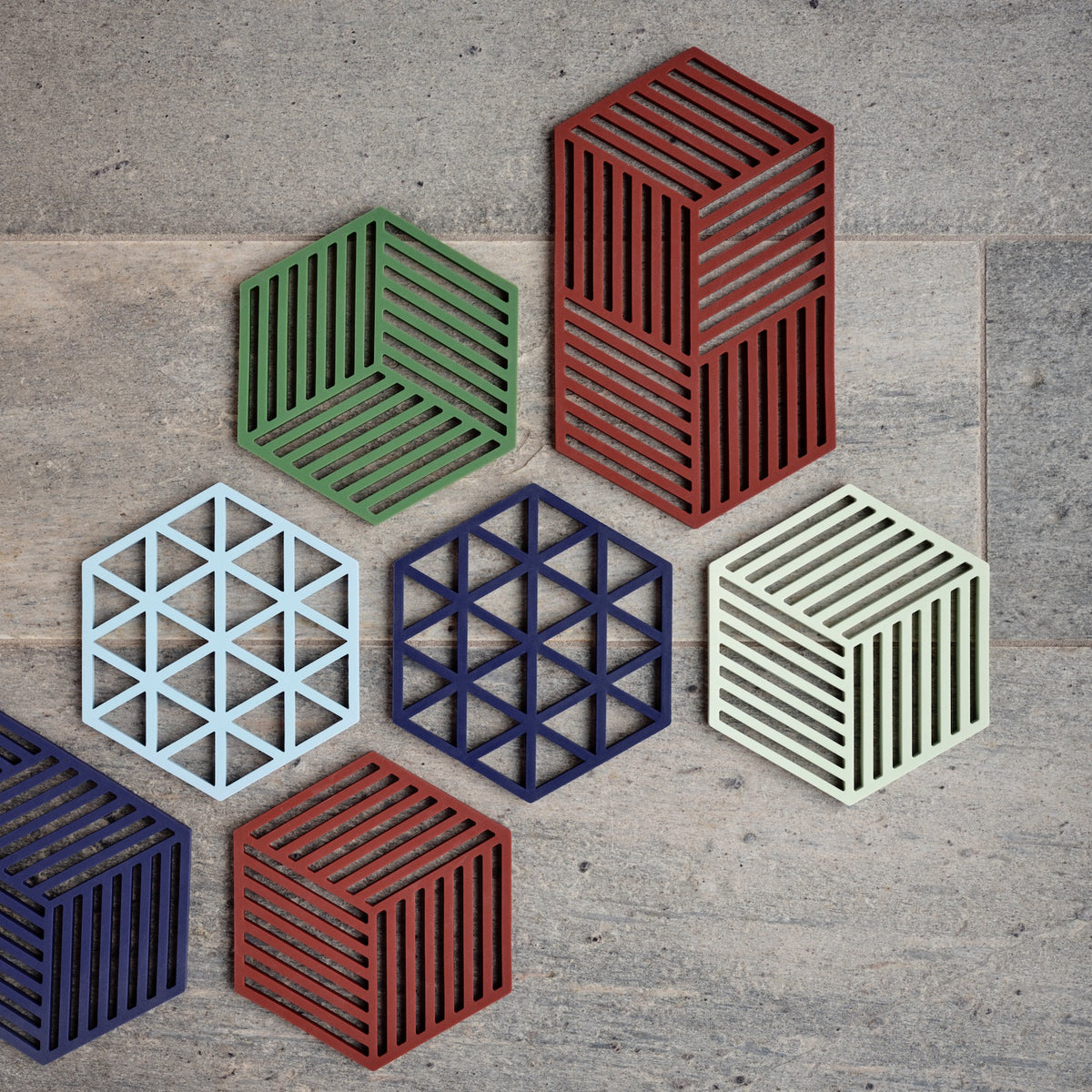 Hexagonal trivets in various colors on a concrete surface