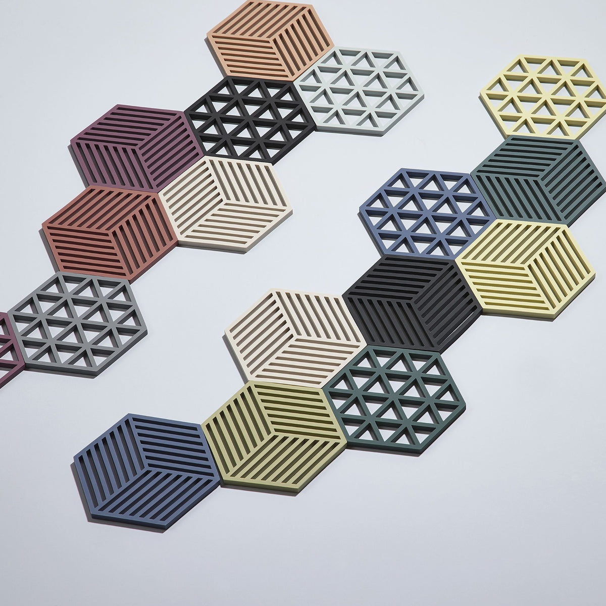 Hexagonal trivets with geometric patterns in various colors on a light gray background