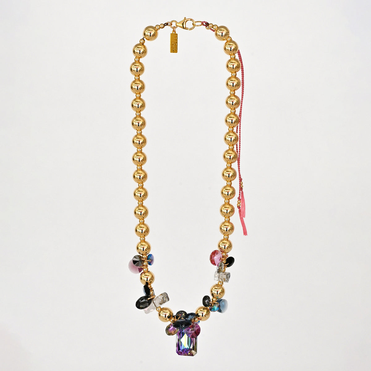 Gold beaded necklace with colorful crystals on a white background