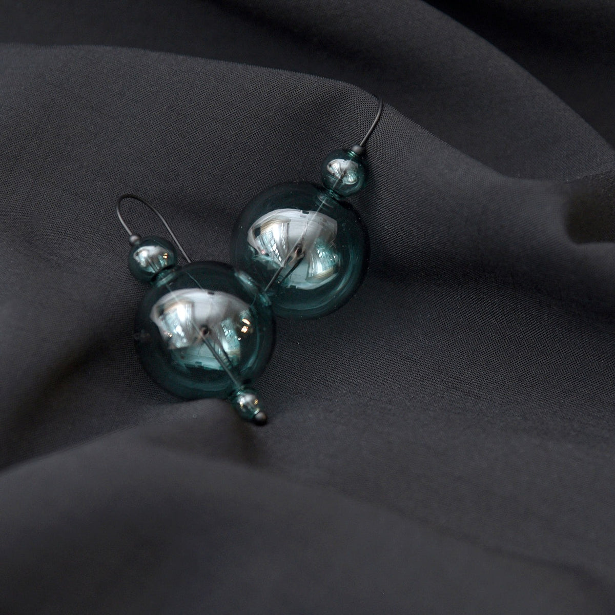 Earrings on dark cloth background.