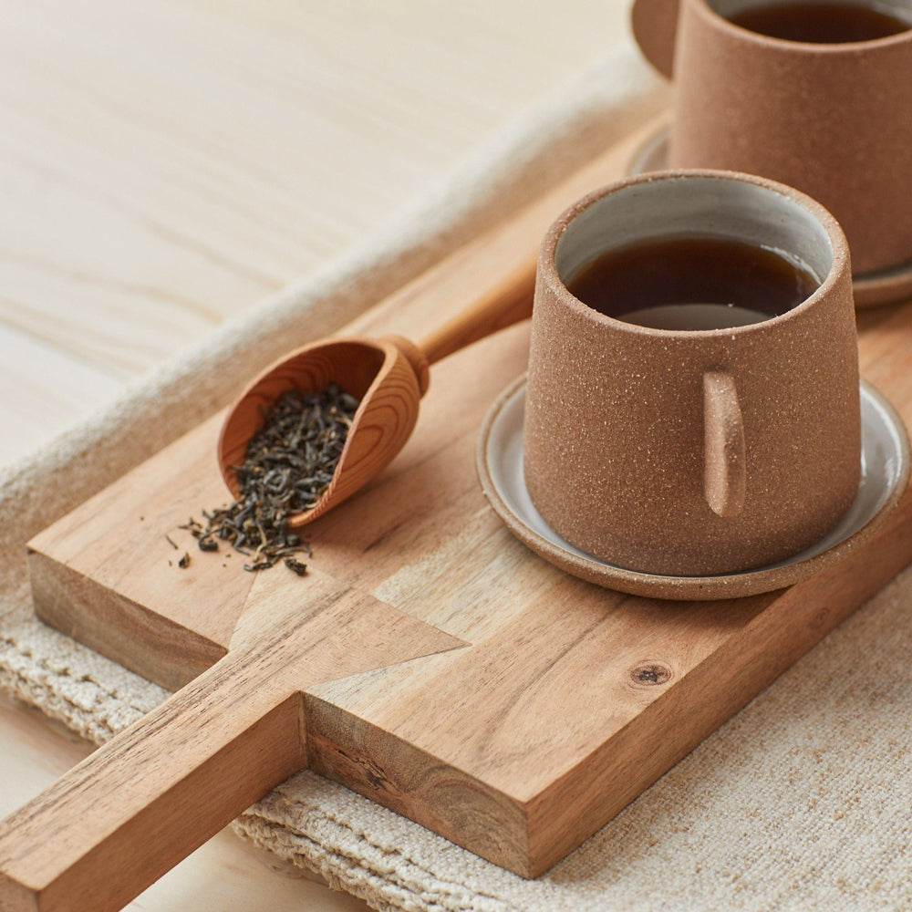 Clay cup on wooden board with tea.