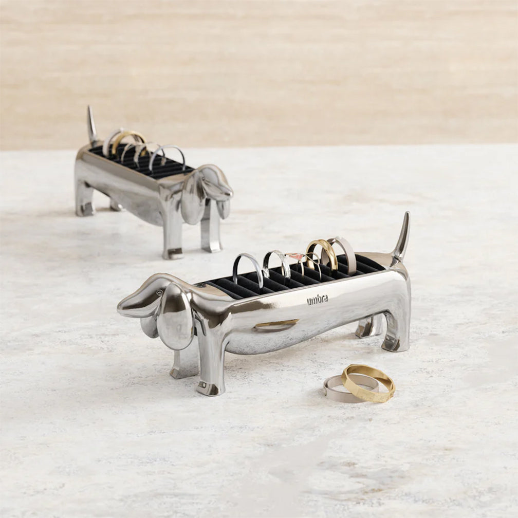 Two silver dachshund-shaped ring holders on a light surface.