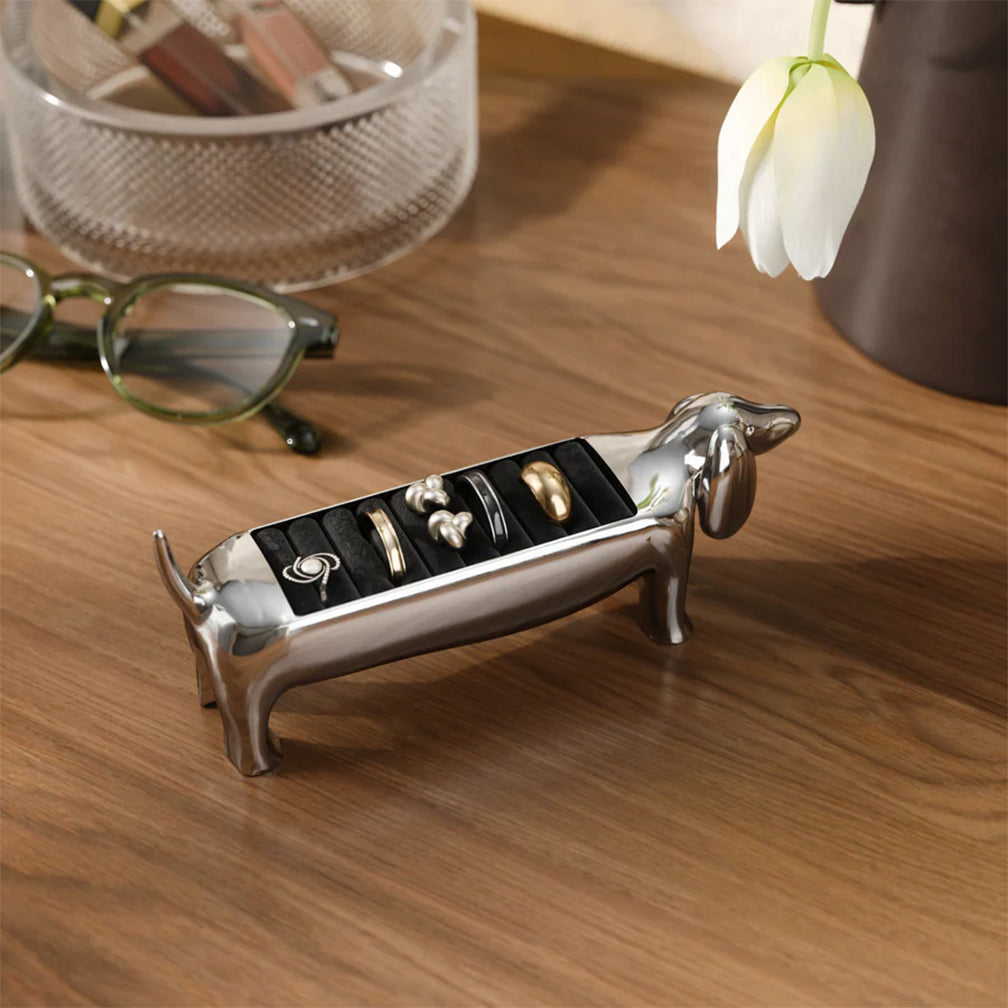 Dog-shaped jewelry holder with rings on a wooden surface