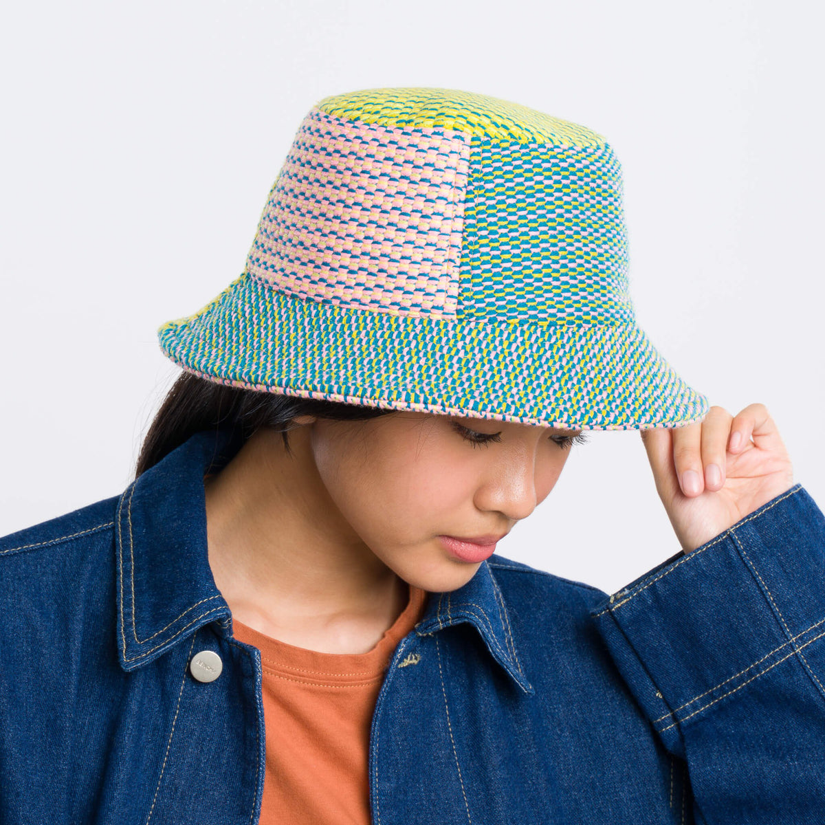 Person wearing a colorful bucket hat against a white background