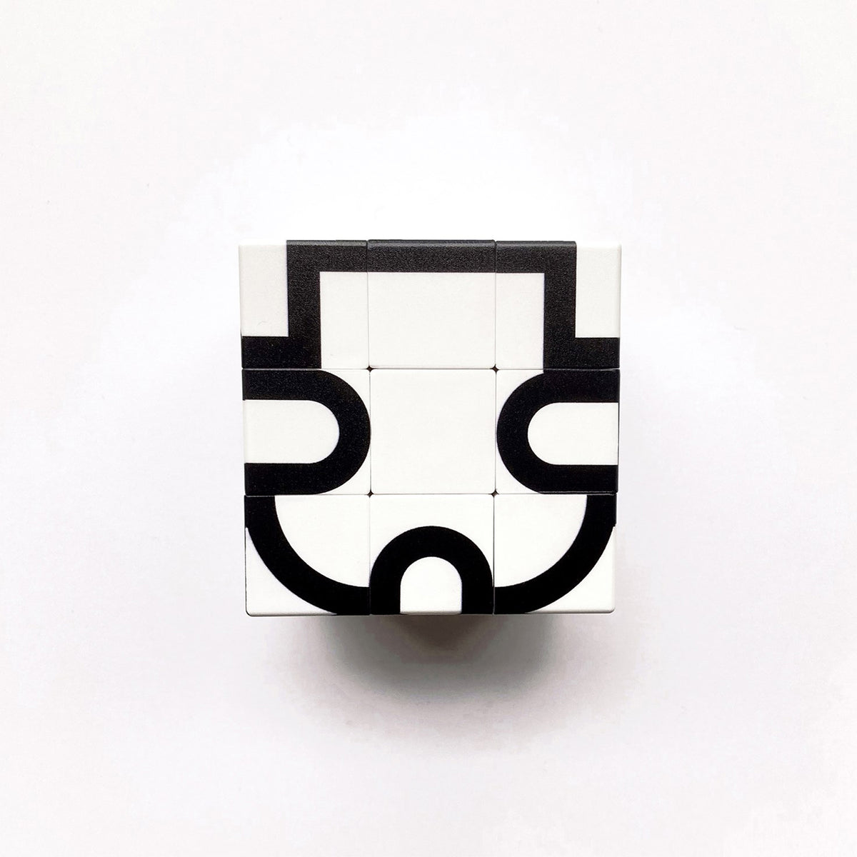 A white square puzzle box with black geometric line art, photographed from above on a plain white background.