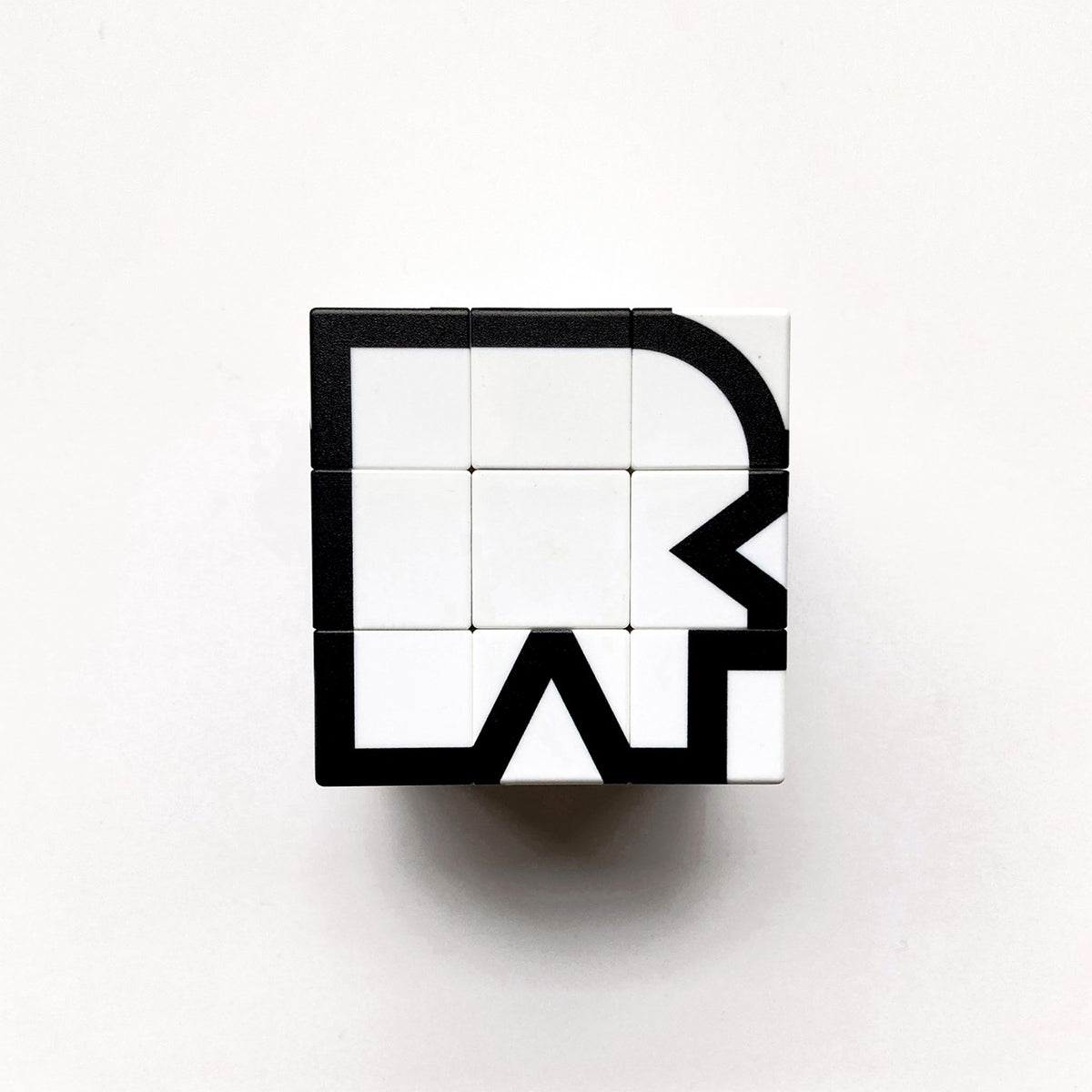 A 3x3 cube-shaped puzzle block featuring a black and white geometric design, photographed from directly above on a clean white background.