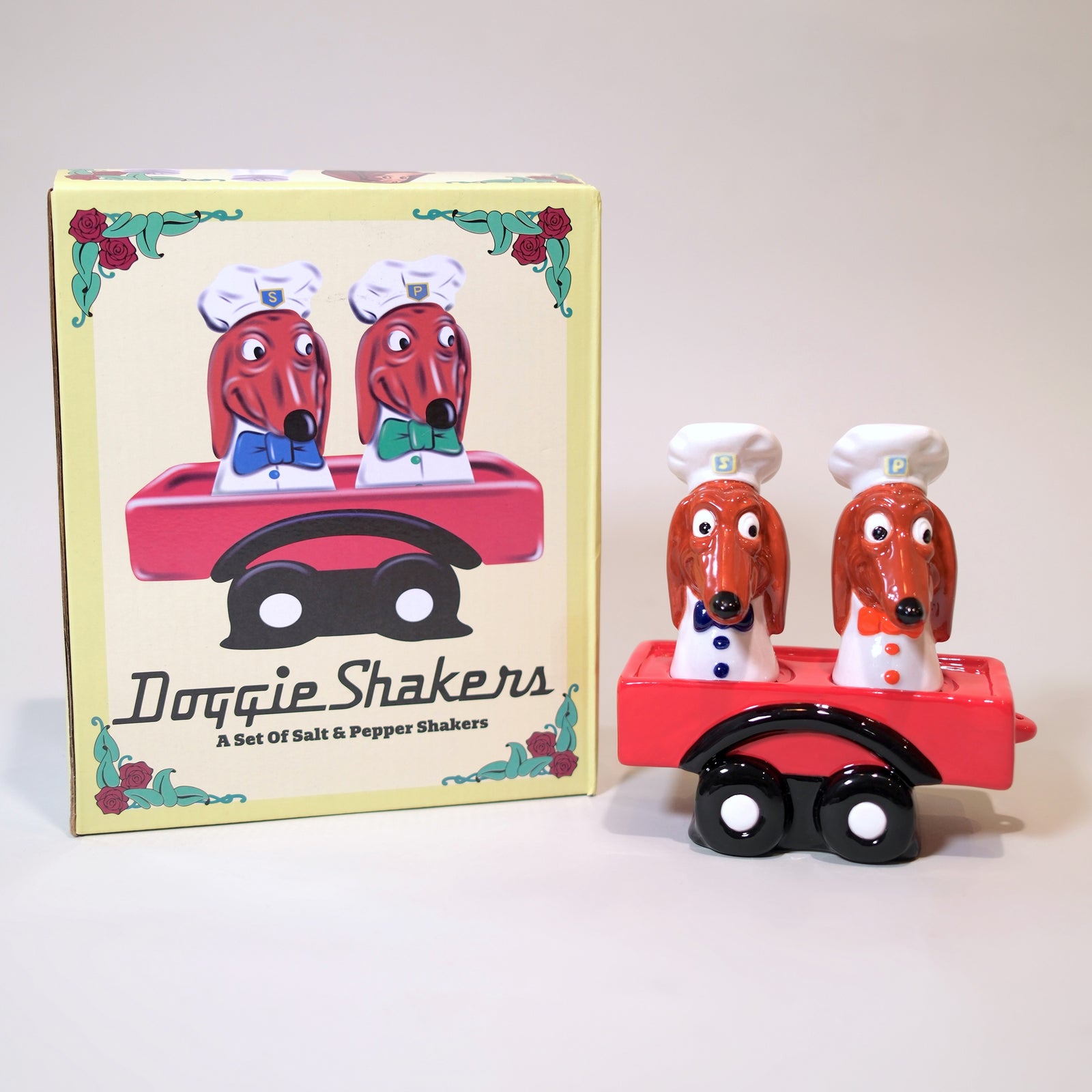 Two dog-shaped salt and pepper shakers with a red cart on a white background