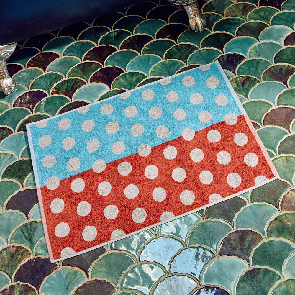 Polka bathmat with blue and red sections on a green mosaic background