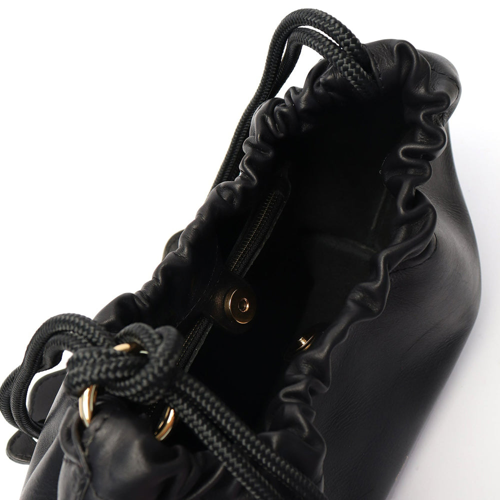 Black leather shoulder bag with ruched detail, asymmetrical knotted strap, and a magnetic fastening. It features an extra long strap and comes with a detachable zip pouch.