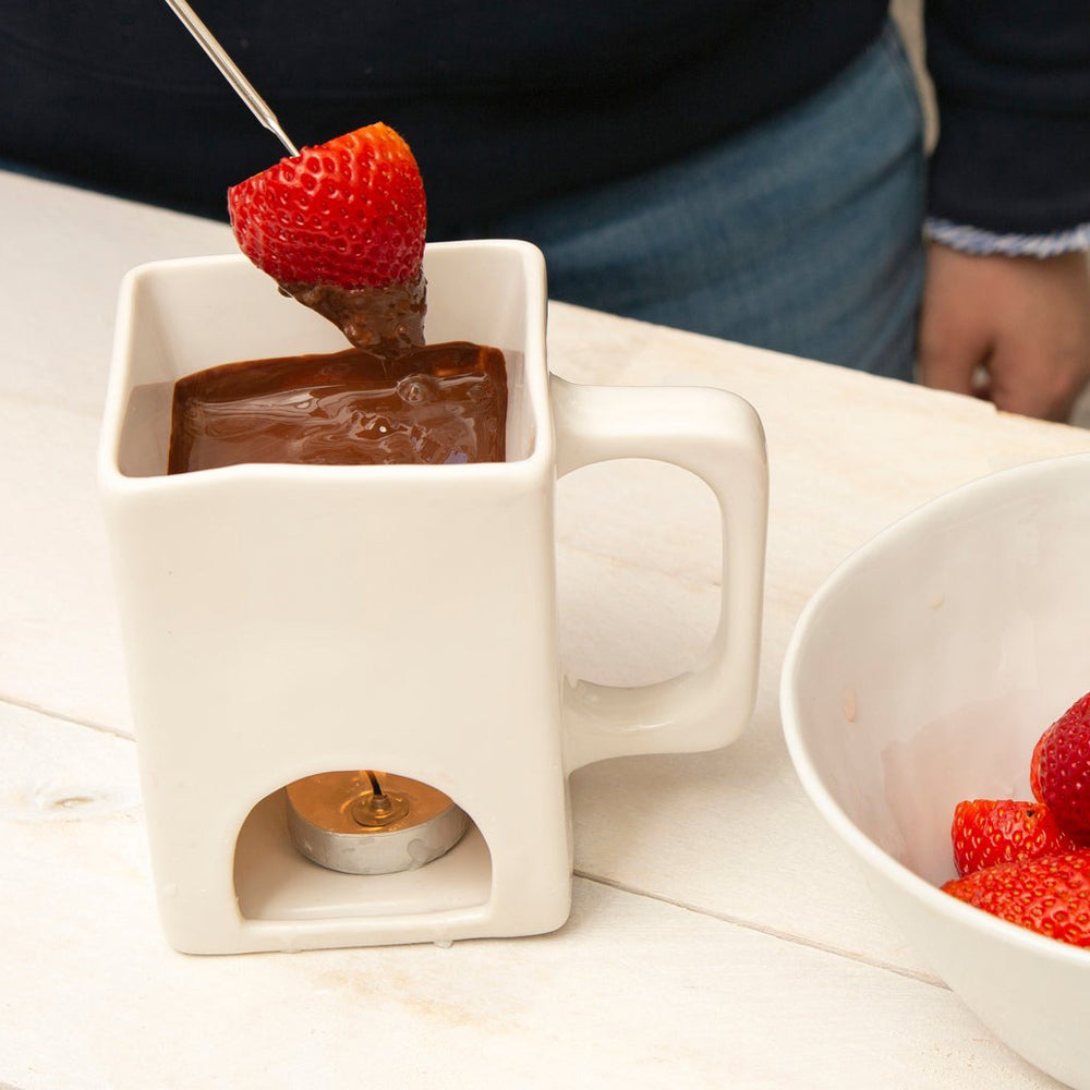 Model dipping strawberry in fondue pot.