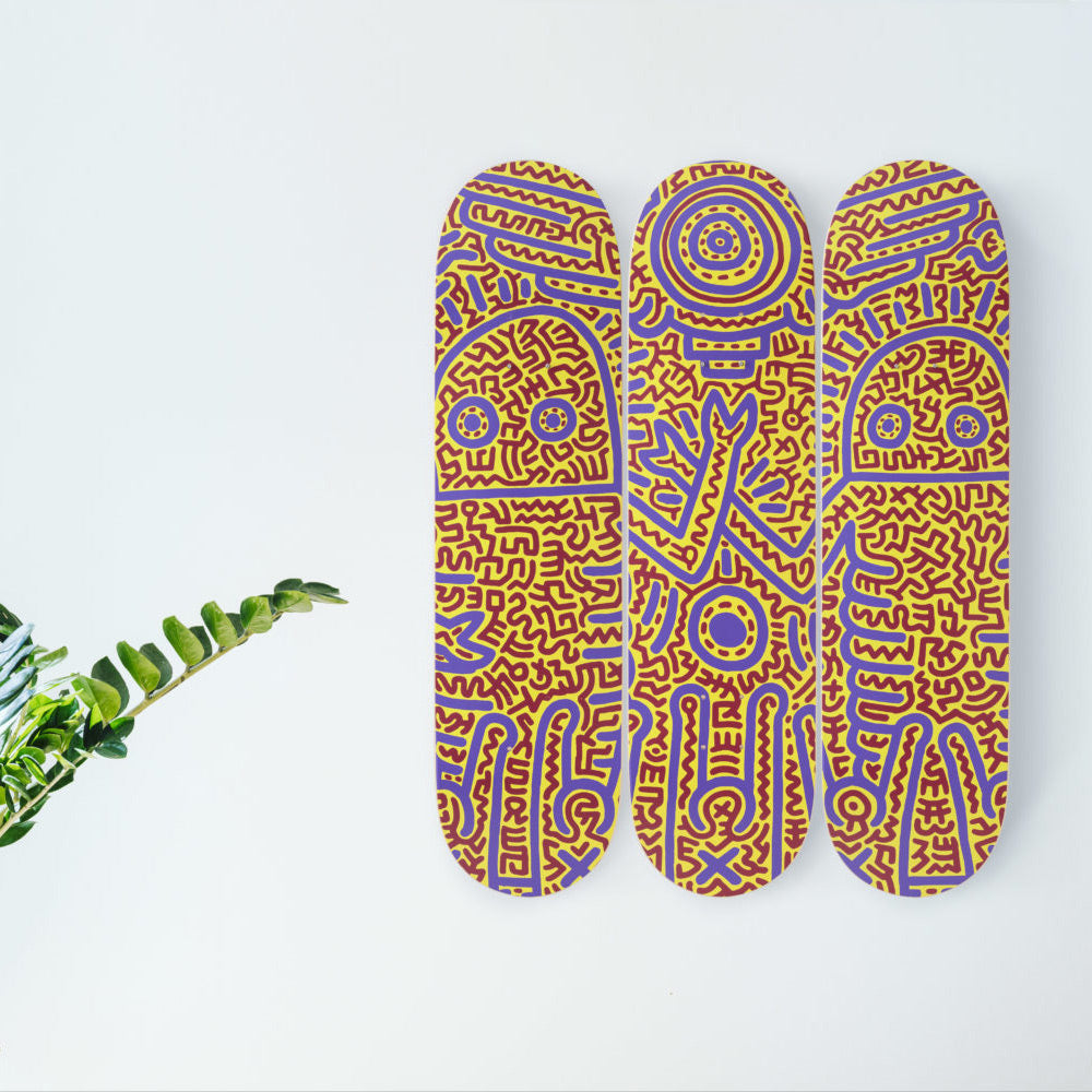 Triptych skateboards hanging on wall with plant.