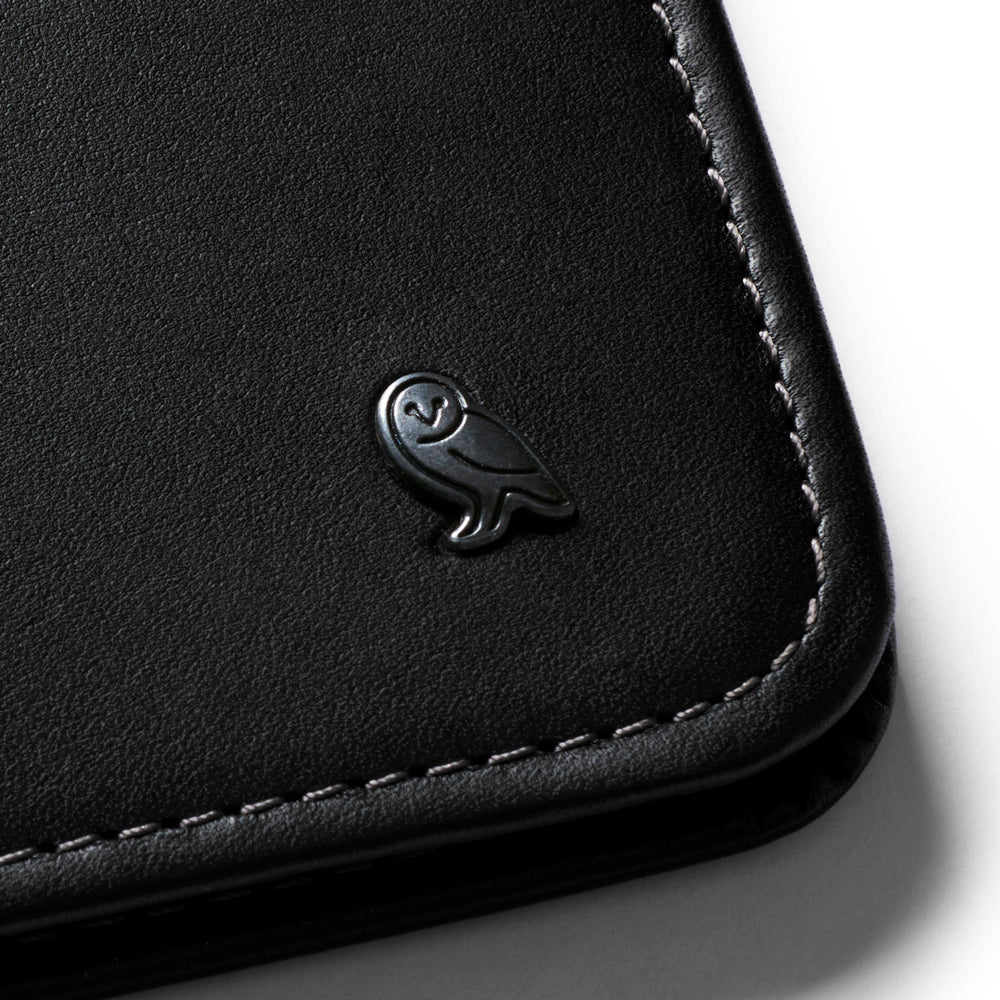 Close-up view of metal owl icon on corner of wallet.